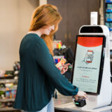 Mapco store woman scanning phone at self checkout