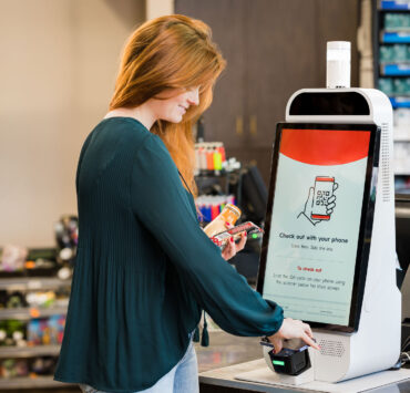Mapco store woman scanning phone at self checkout