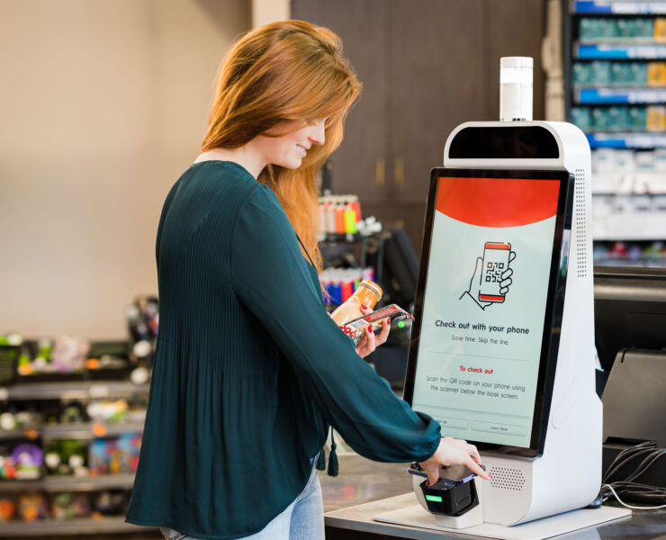 Mapco store woman scanning phone at self checkout