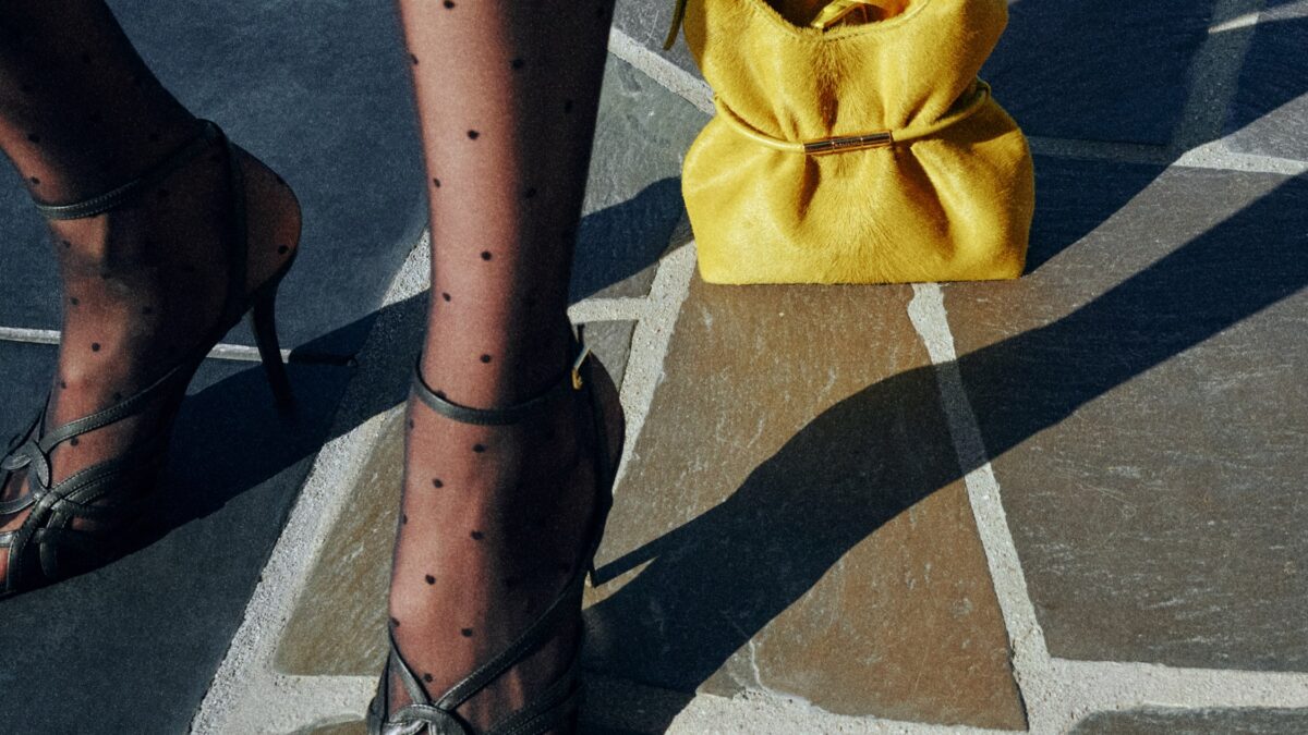 Yellow Balmain Sphynx bag in pony-effect leather styled with polka-dot stockings and heels on a stone street