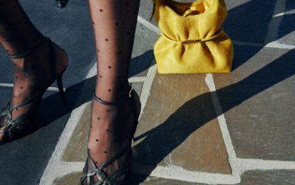 Yellow Balmain Sphynx bag in pony-effect leather styled with polka-dot stockings and heels on a stone street