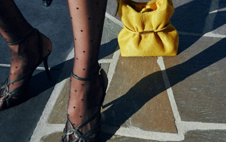 Yellow Balmain Sphynx bag in pony-effect leather styled with polka-dot stockings and heels on a stone street