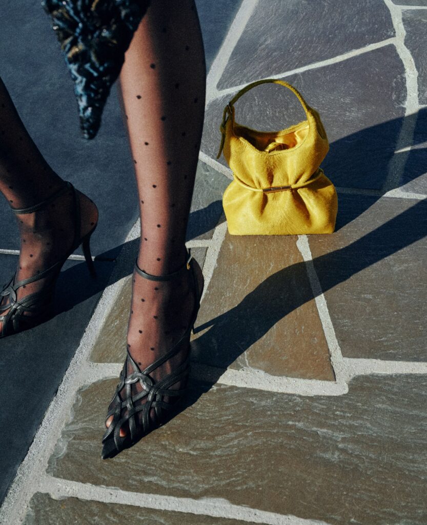 Yellow Balmain Sphynx bag in pony-effect leather styled with polka-dot stockings and heels on a stone street