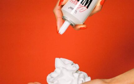 A hand dispenses Vacation Classic Whip SPF 30 sunscreen from its whipped-cream-style can.