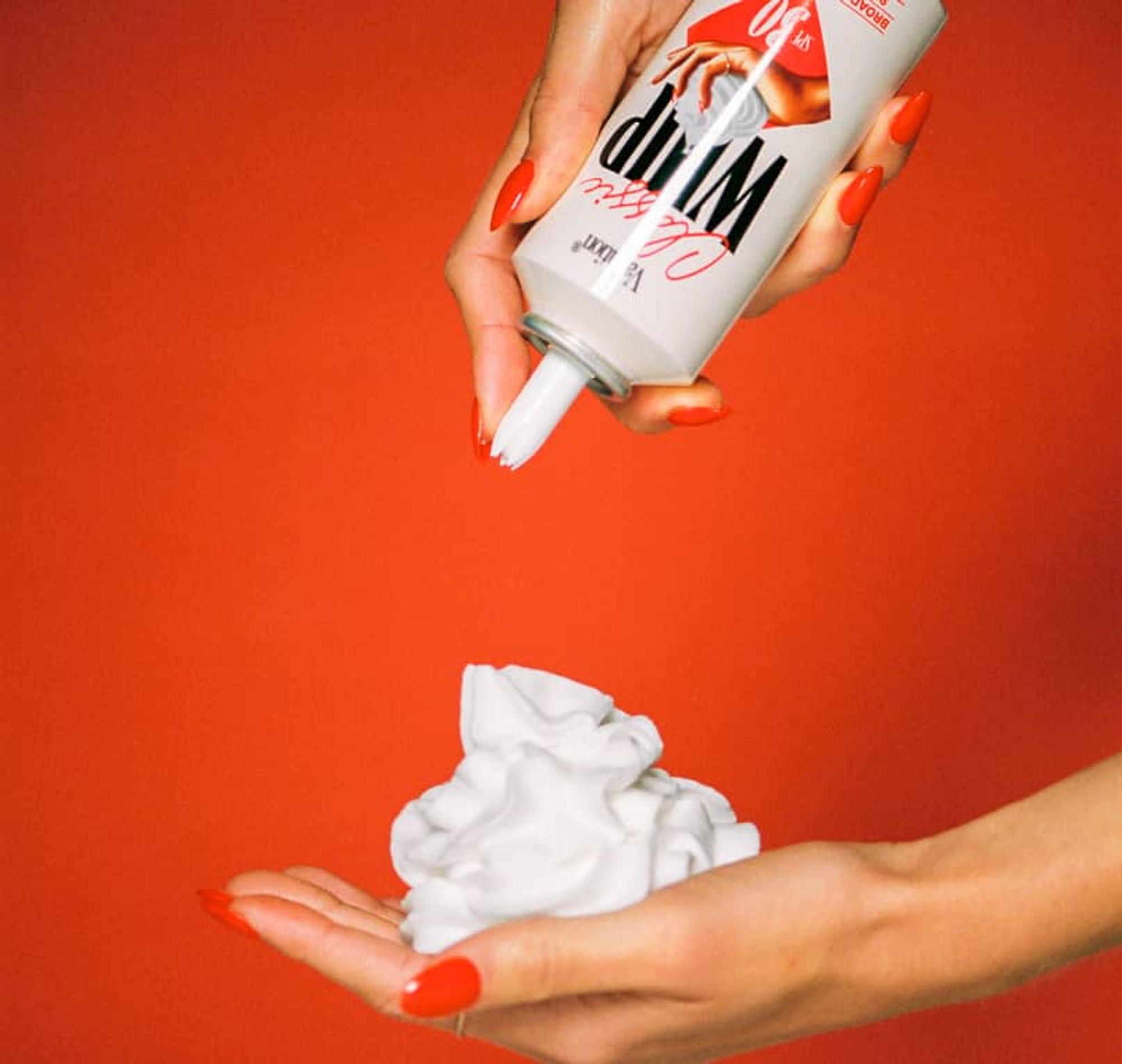 A hand dispenses Vacation Classic Whip SPF 30 sunscreen from its whipped-cream-style can.