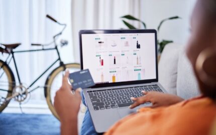Online shopper browsing beauty products on a laptop while holding a payment card
