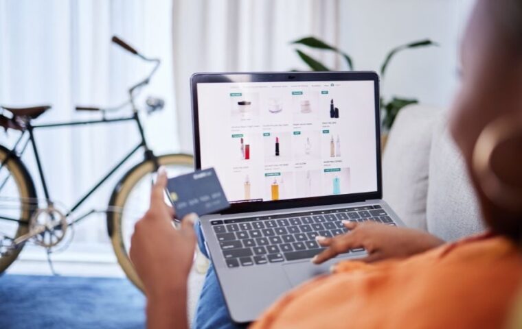 Online shopper browsing beauty products on a laptop while holding a payment card