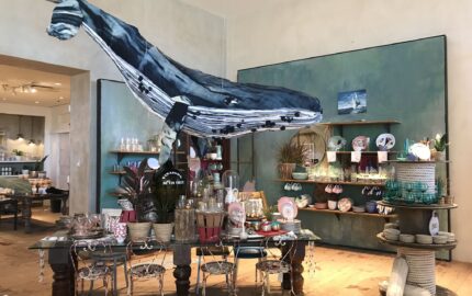 An oversized denim whale suspended above Anthropologie homeware tables and shelves