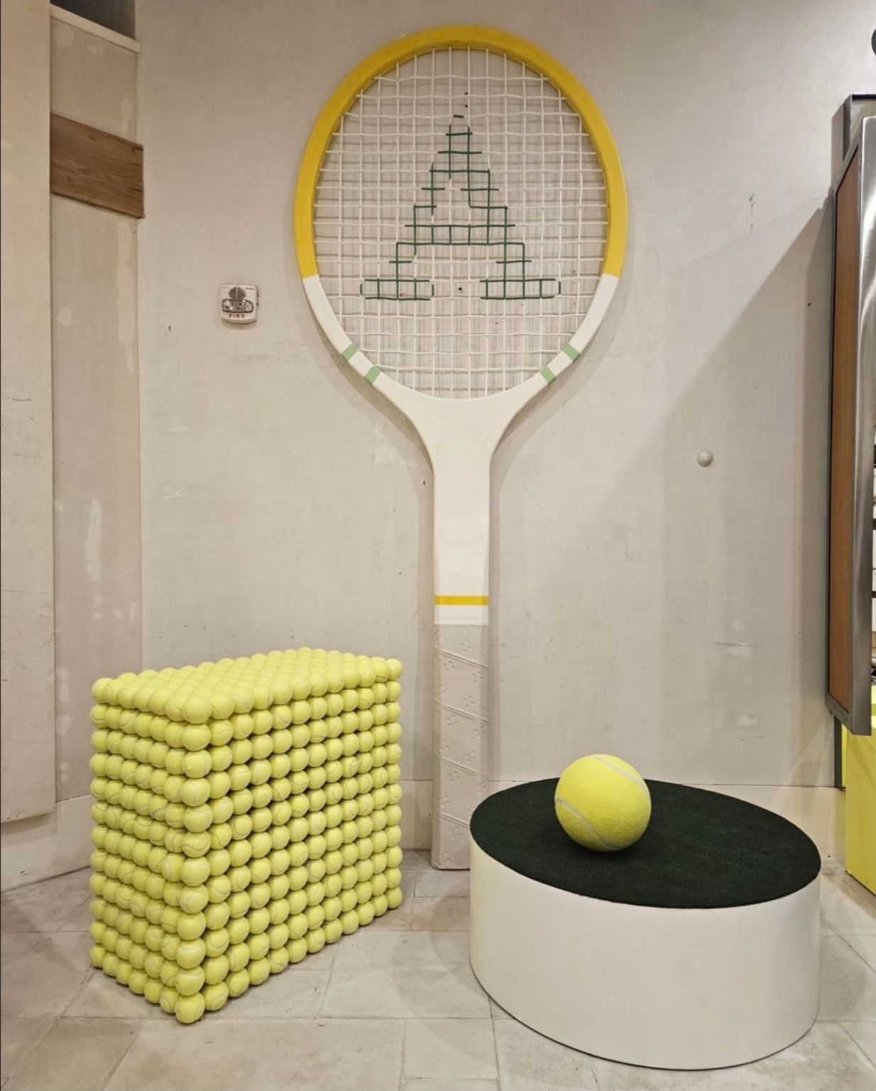 Giant tennis racket and a cube covered in tennis balls in an Anthropologie display