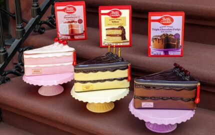 Three Betty Crocker cake-slice handbags displayed with corresponding cake mix boxes