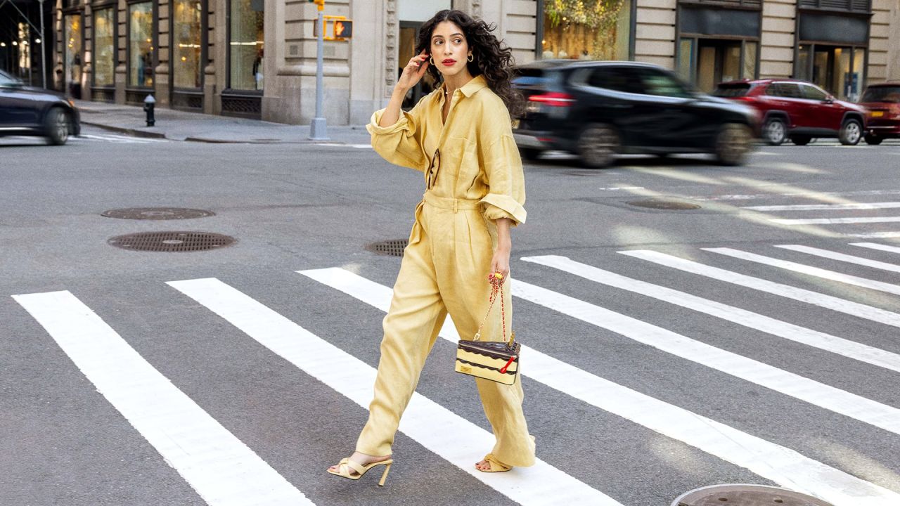 Model in a yellow outfit carrying the Betty Ate Yellow Cake handbag across a city street