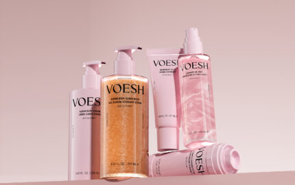 Pink VOESH body-care packaging arranged on a pink background.