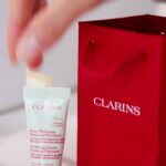 Clarins sample tube beside a red Clarins bag in its Eco Top packaging video