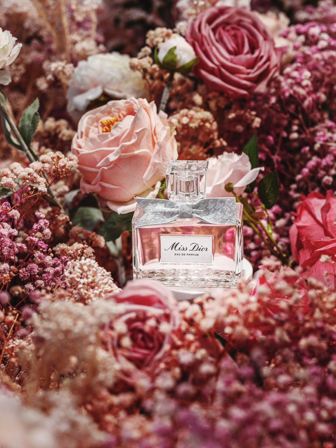 Miss Dior Eau de Parfum bottle among pink flowers