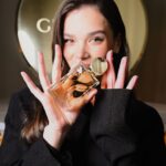 Hailee Steinfeld holds Estée Lauder Glimmer fragrance at the New York launch event