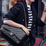 Model wearing a black CHANEL jacket and carrying a quilted CHANEL handbag in campaign imagery.