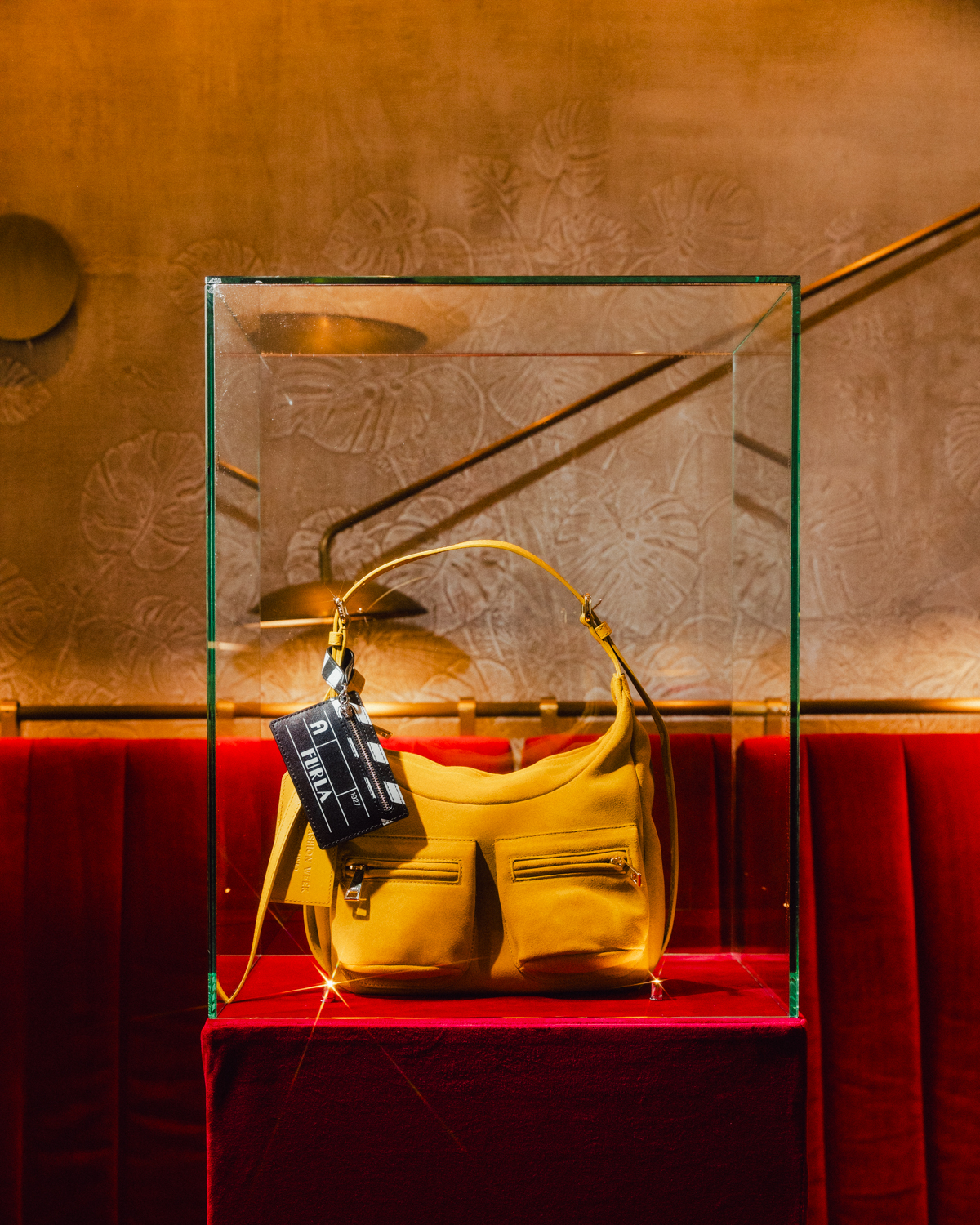 Yellow Furla Lynette bag displayed in a glass case