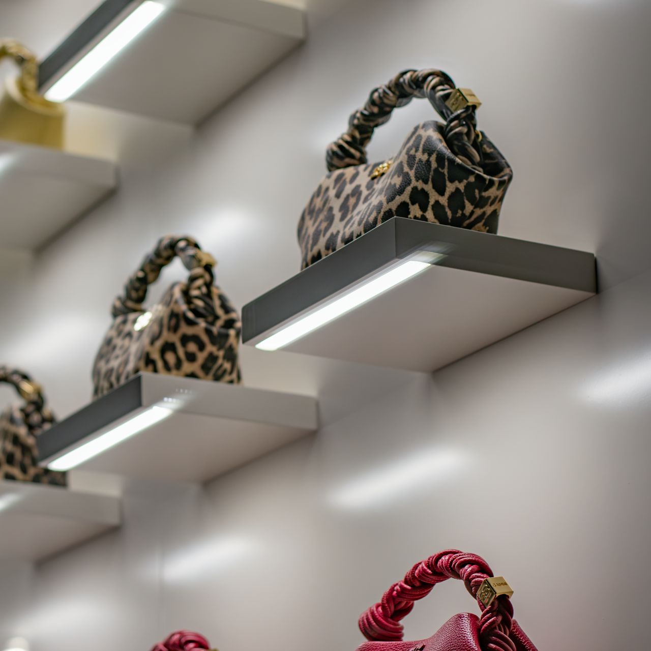 GANNI Bou bags displayed on individually illuminated white shelves