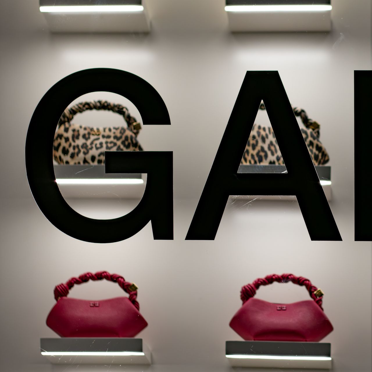 Burgundy and leopard GANNI Bou bags behind the store's window lettering