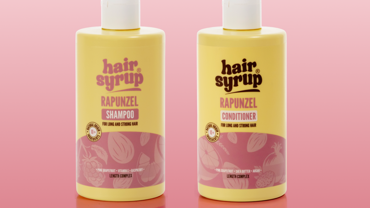Hair Syrup Rapunzel shampoo and conditioner bottles against a pink background.