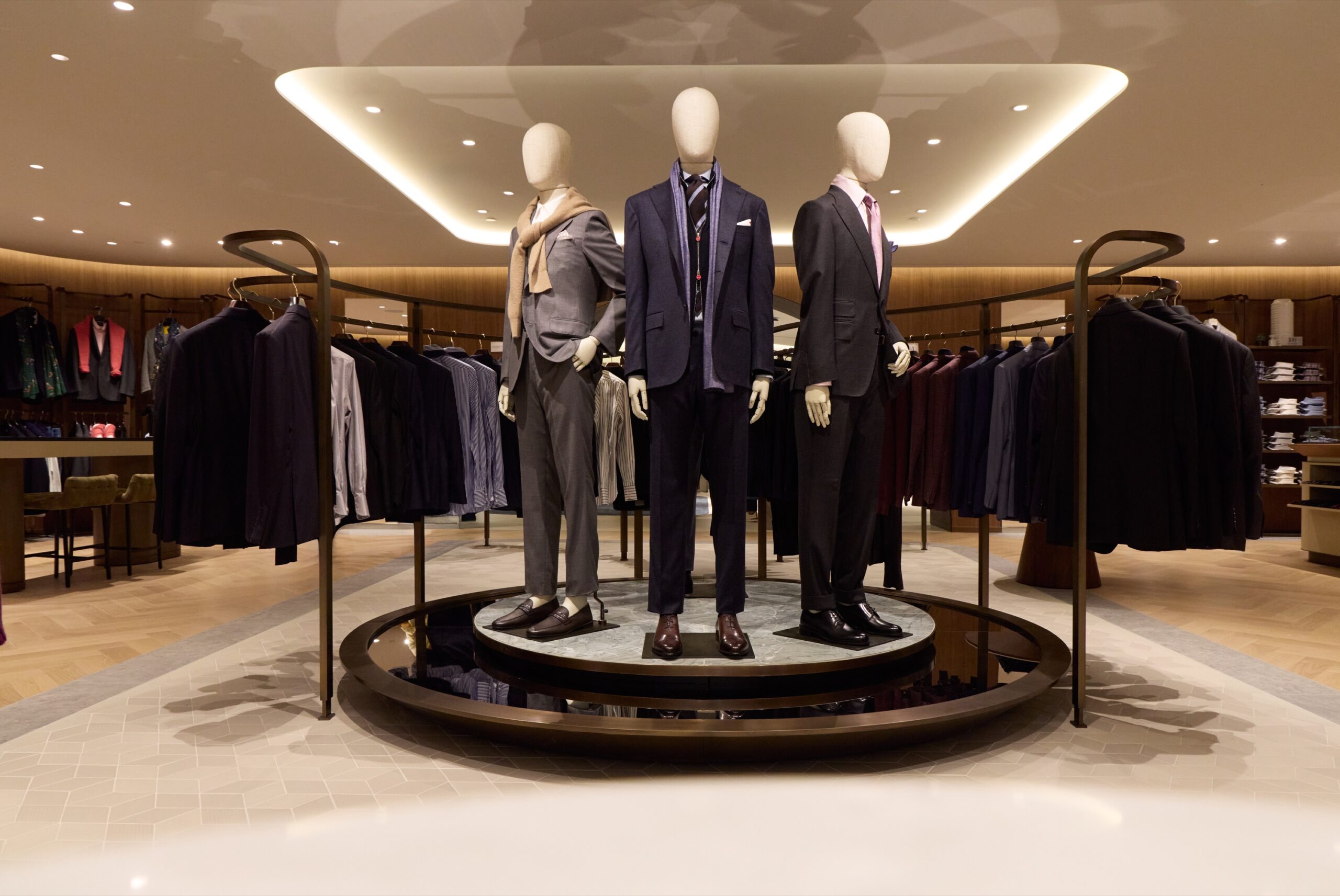Tailored menswear mannequins on a circular display inside Harry Rosen