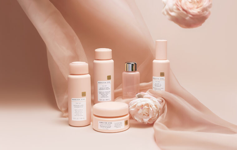 Kristin Ess Hair products arranged with pink flowers.