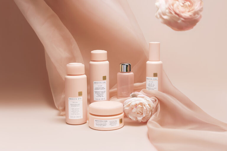 Kristin Ess Hair products arranged with pink flowers.