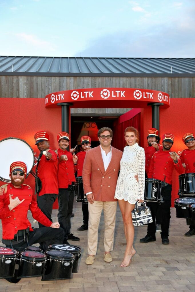 Guests pose with a drumline in red uniforms outside the LTK-branded event entrance