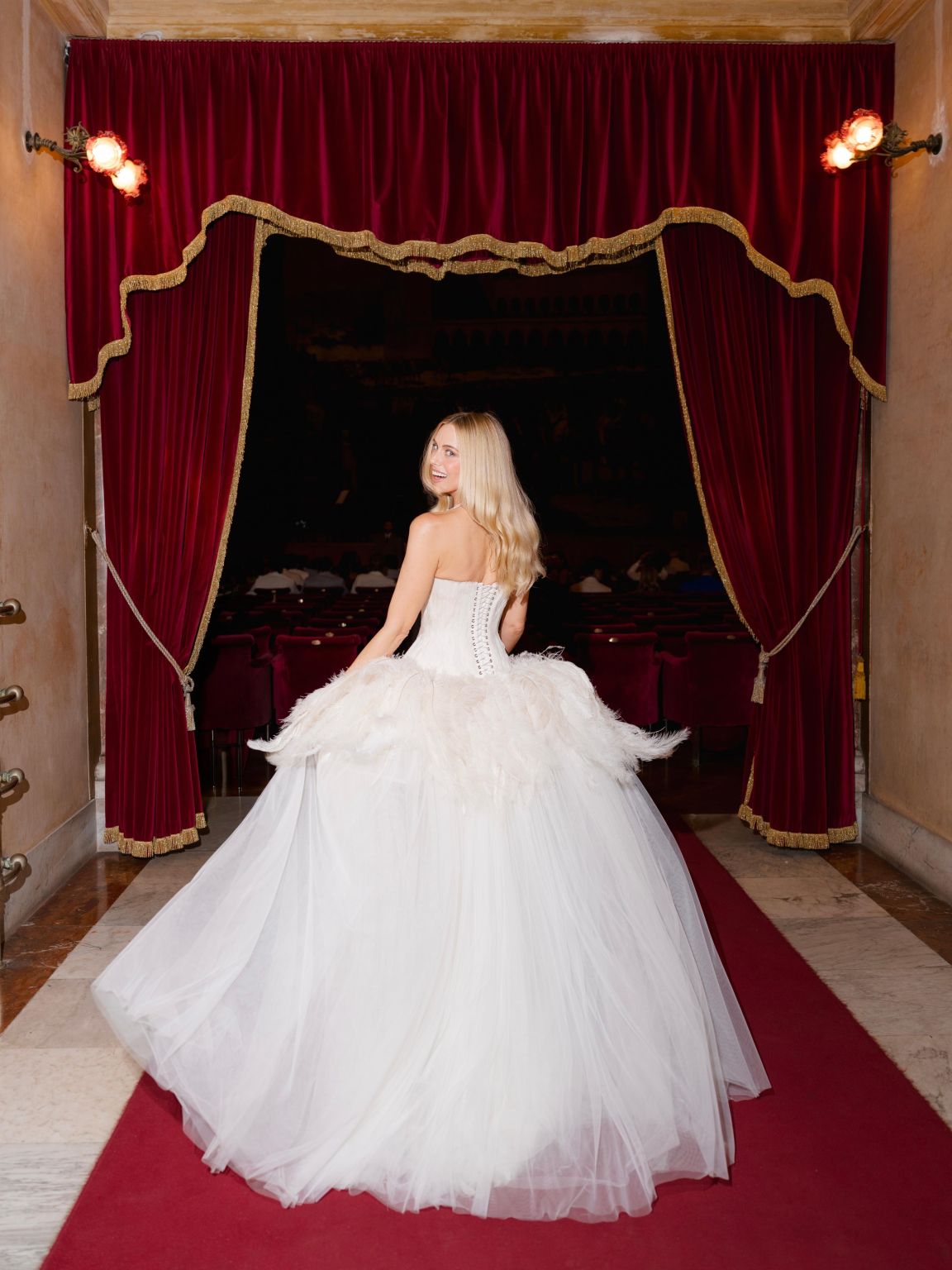 Rear view of Cait Bailey Carbone’s custom gown showing the corseted back and feathered skirt