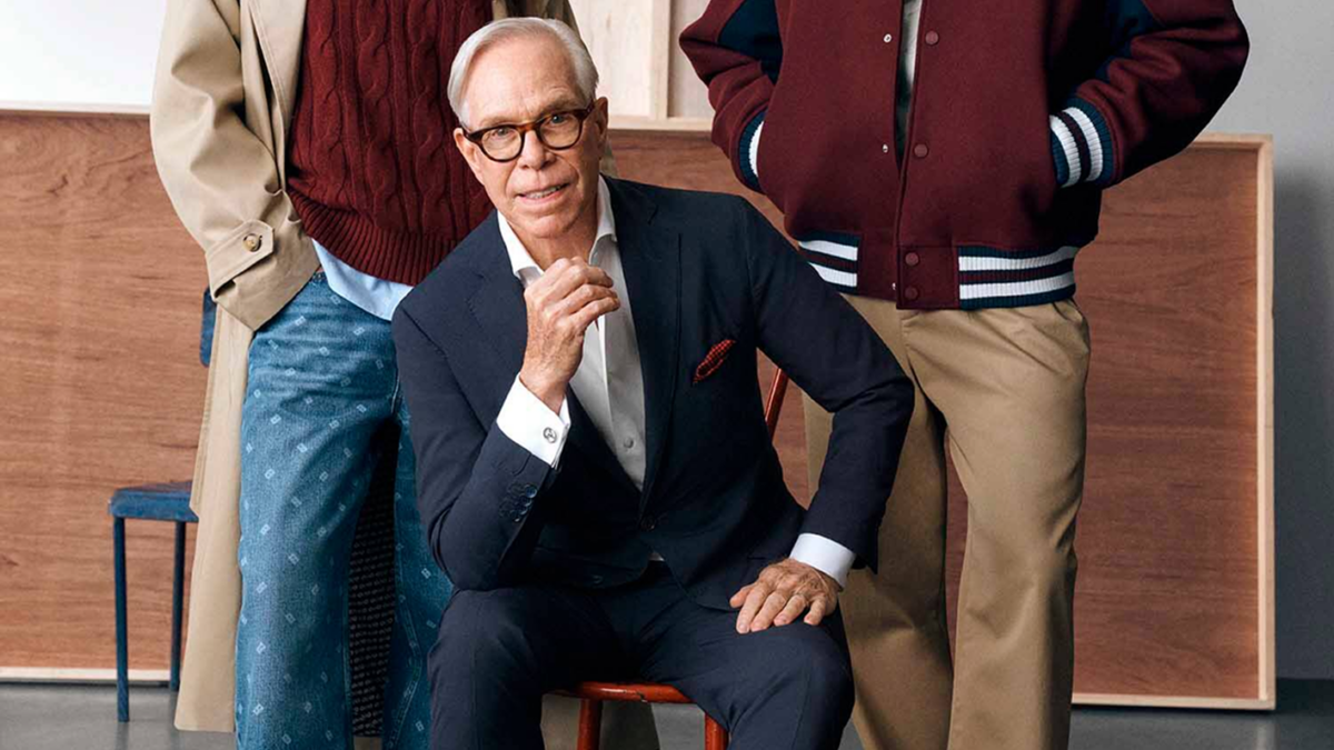 Tommy Hilfiger seated between two models wearing his Macy’s collection.