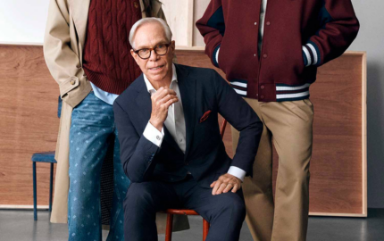 Tommy Hilfiger seated between two models wearing his Macy’s collection.