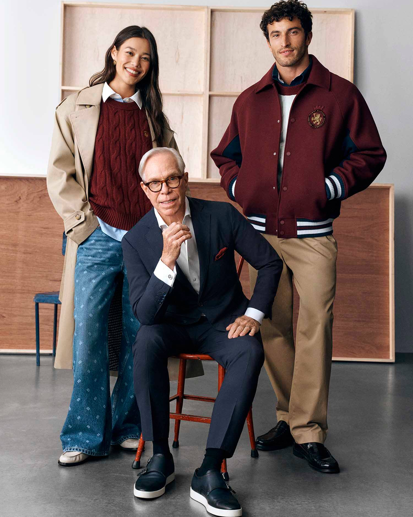 Tommy Hilfiger seated between two models wearing his Macy’s collection.