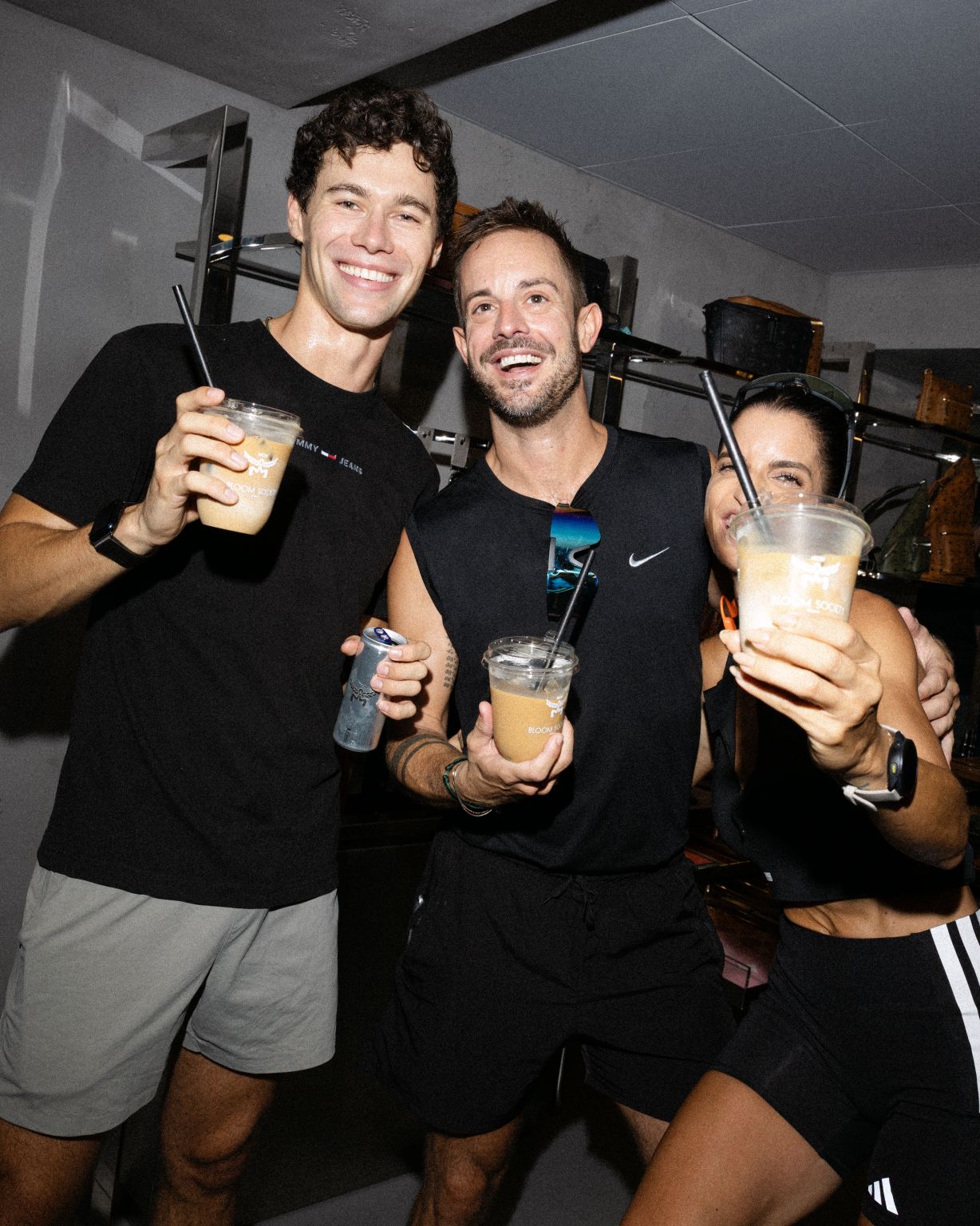 Participants holding drinks beside a display of bags