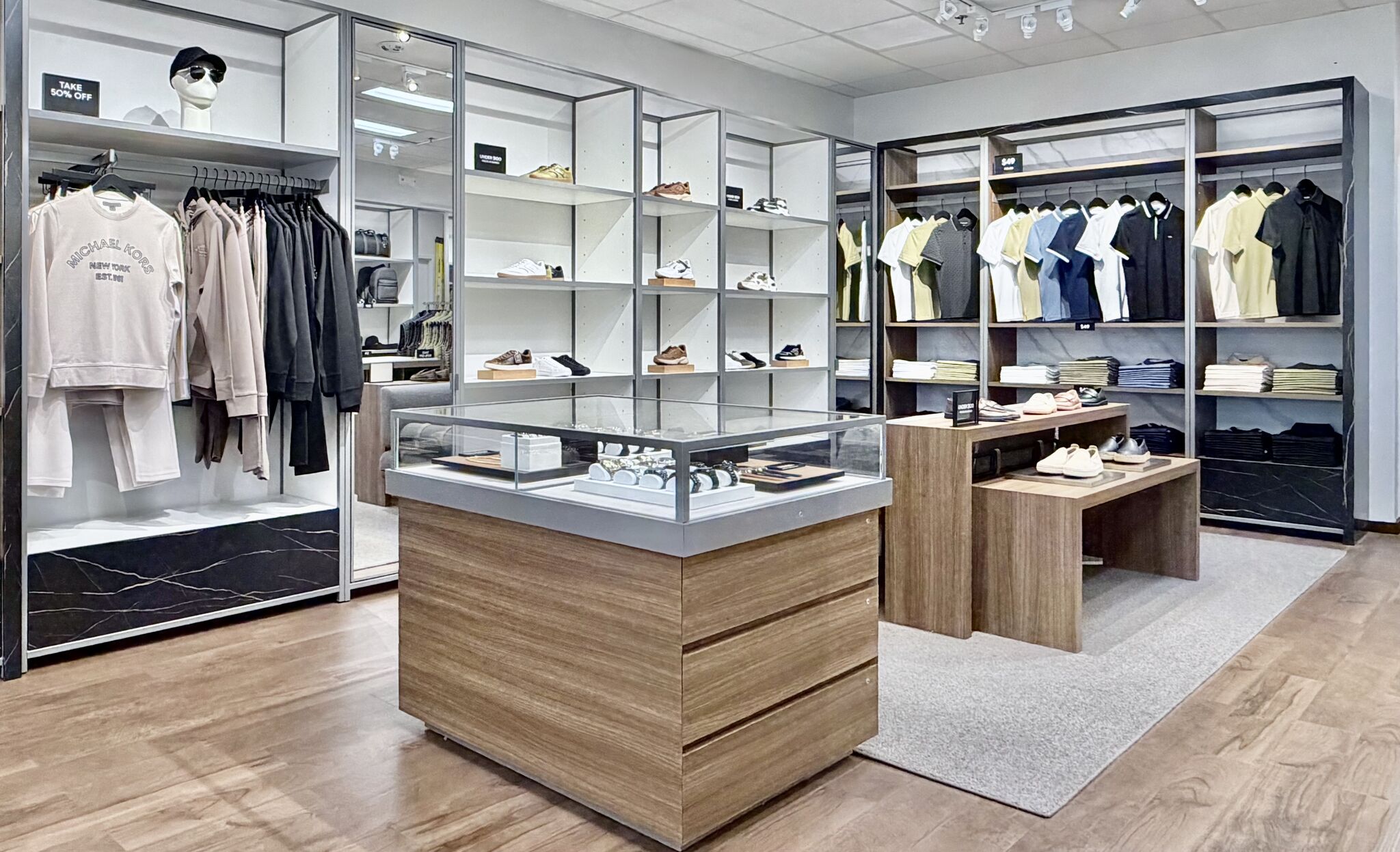 Central tables and hanging apparel at Michael Kors Mens