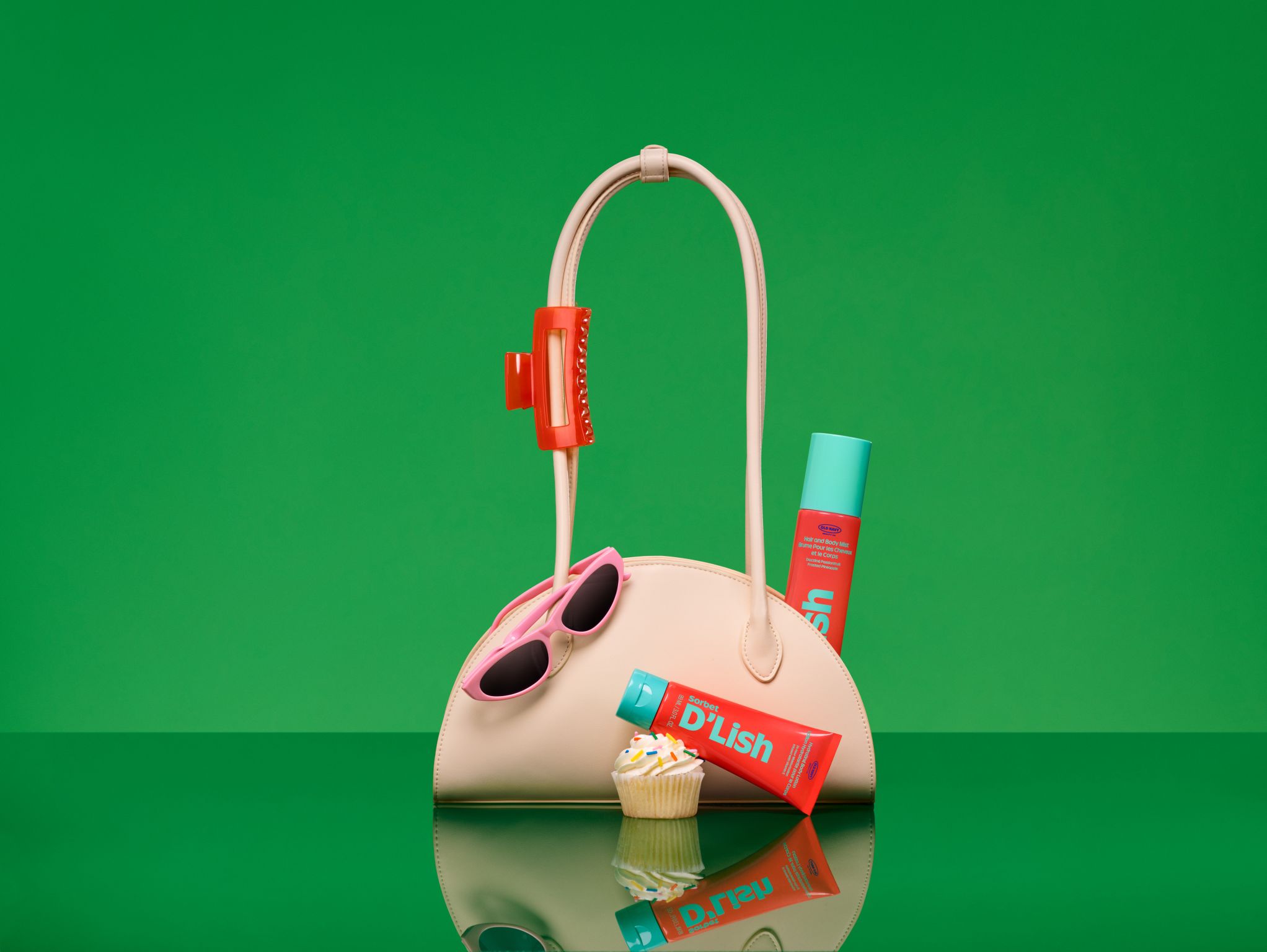 Old Navy Beauty Co. Sorbet D’lish products styled with a handbag on a green background