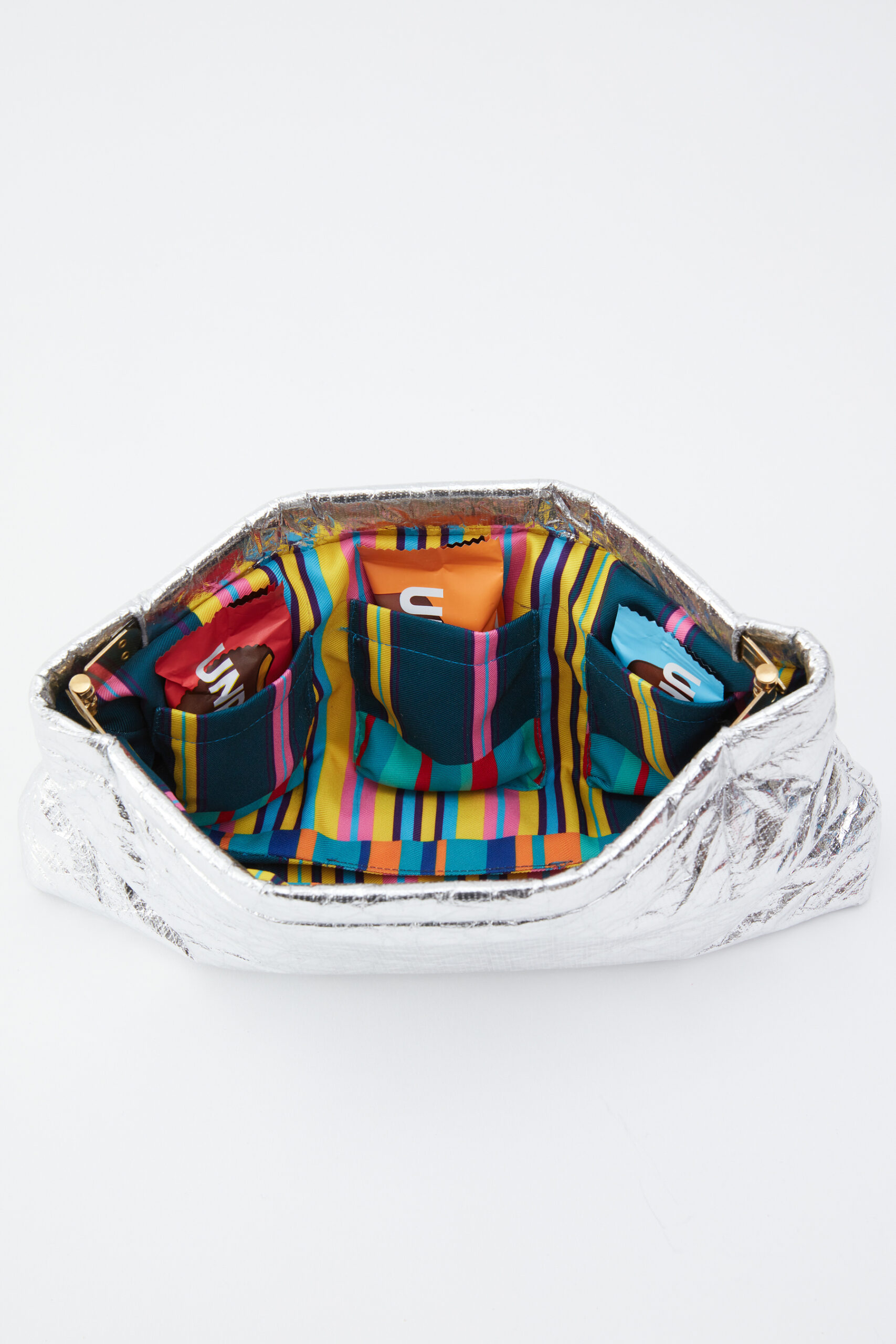 Silver Coco Bag with striped lining and packaged Unreal snacks.
