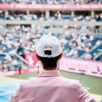 Guest wearing a white Pink Pony cap overlooking the US Open court.