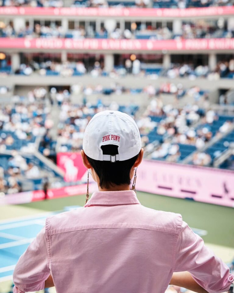 Guest wearing a white Pink Pony cap overlooking the US Open court.