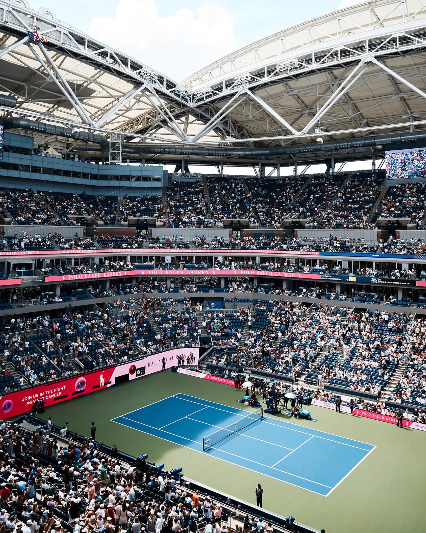 US Open stadium with pink Ralph Lauren signage surrounding the court.