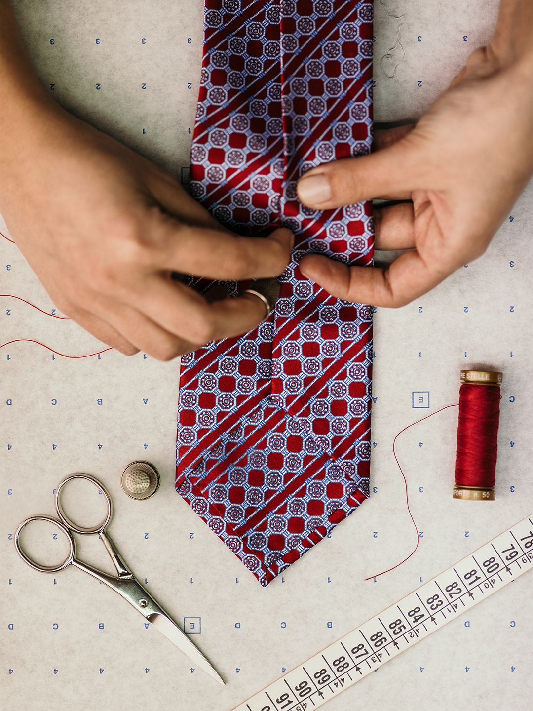Hands working on a patterned Stefano Ricci silk tie