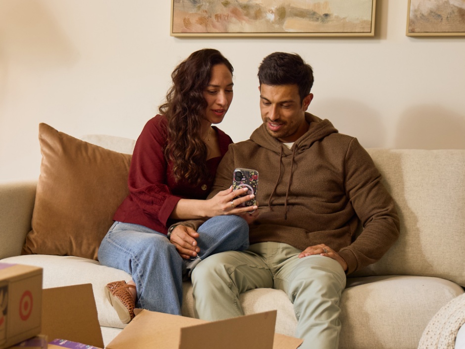 Two shoppers browse products on a phone beside a Target delivery box