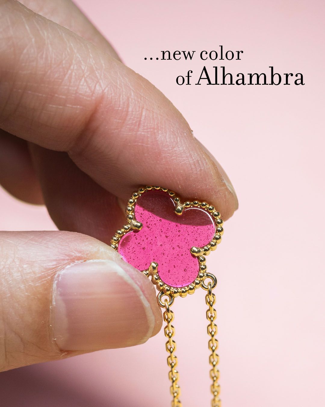 Close view of the translucent pink enamel in an Alhambra pendant held by a craftsperson