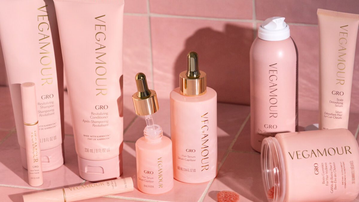 Vegamour haircare products arranged against pink tiles.