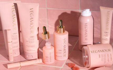 Vegamour haircare products arranged against pink tiles.