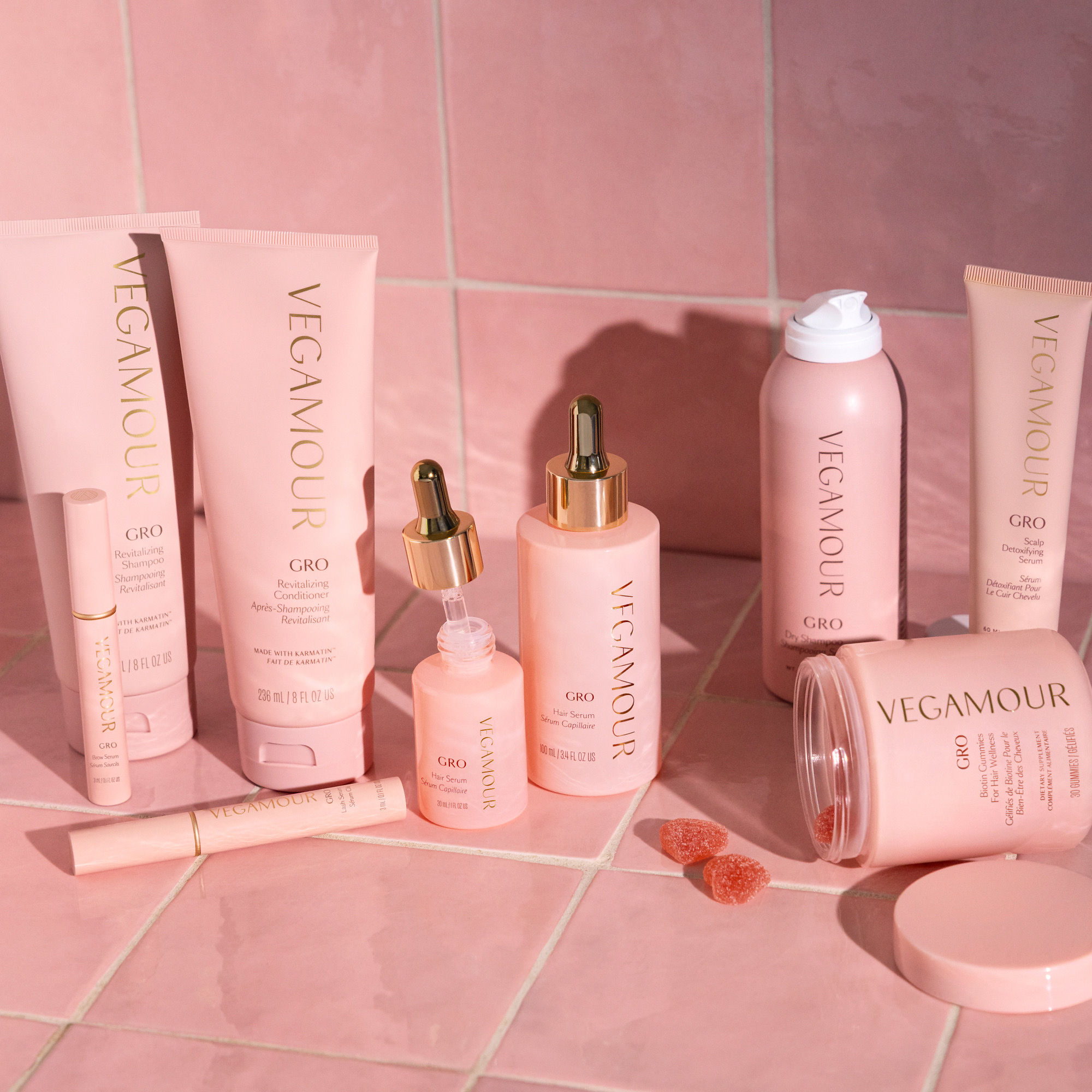 Vegamour haircare products arranged against pink tiles.