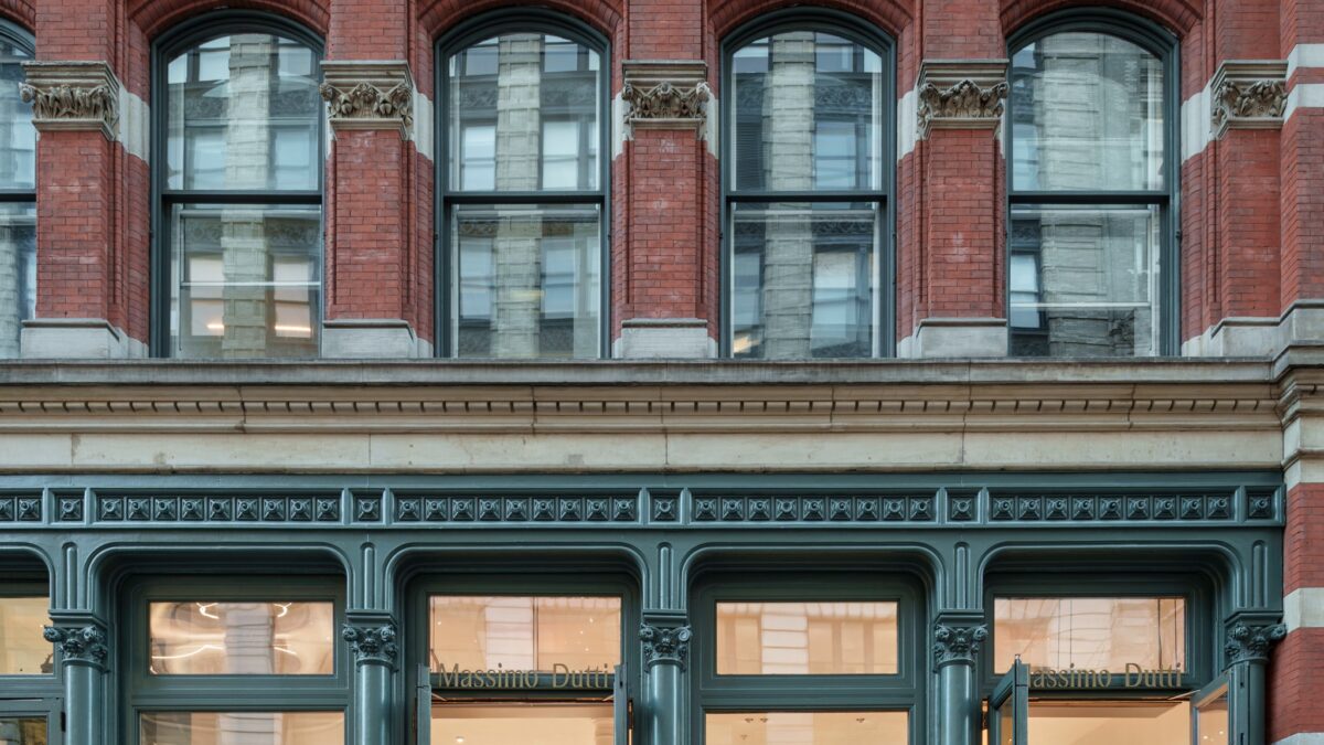 Massimo Dutti SoHo storefront beneath the red brick facade and stone-trimmed windows.