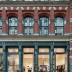 Massimo Dutti SoHo storefront beneath the red brick facade and stone-trimmed windows.
