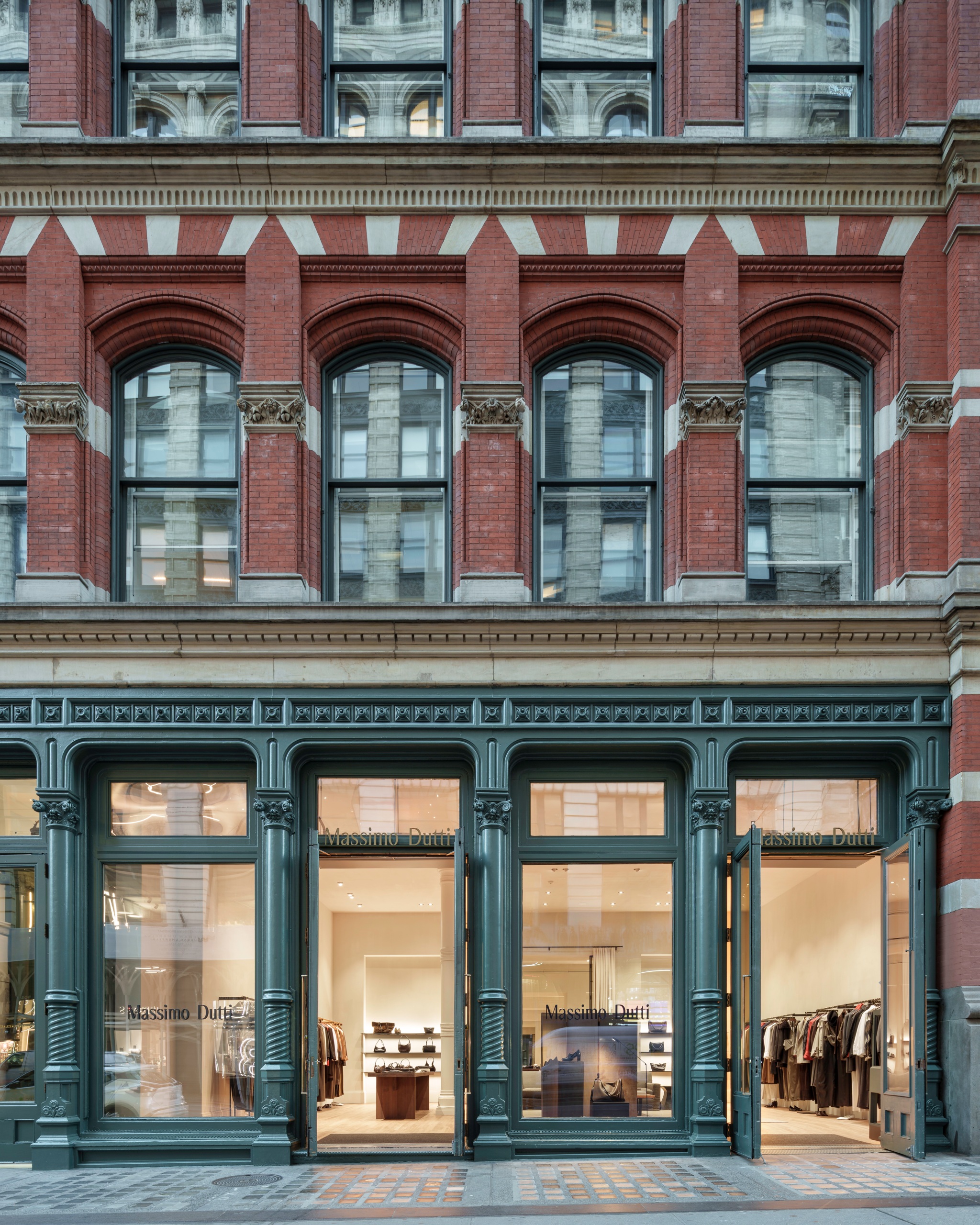 Massimo Dutti SoHo storefront beneath the red brick facade and stone-trimmed windows.