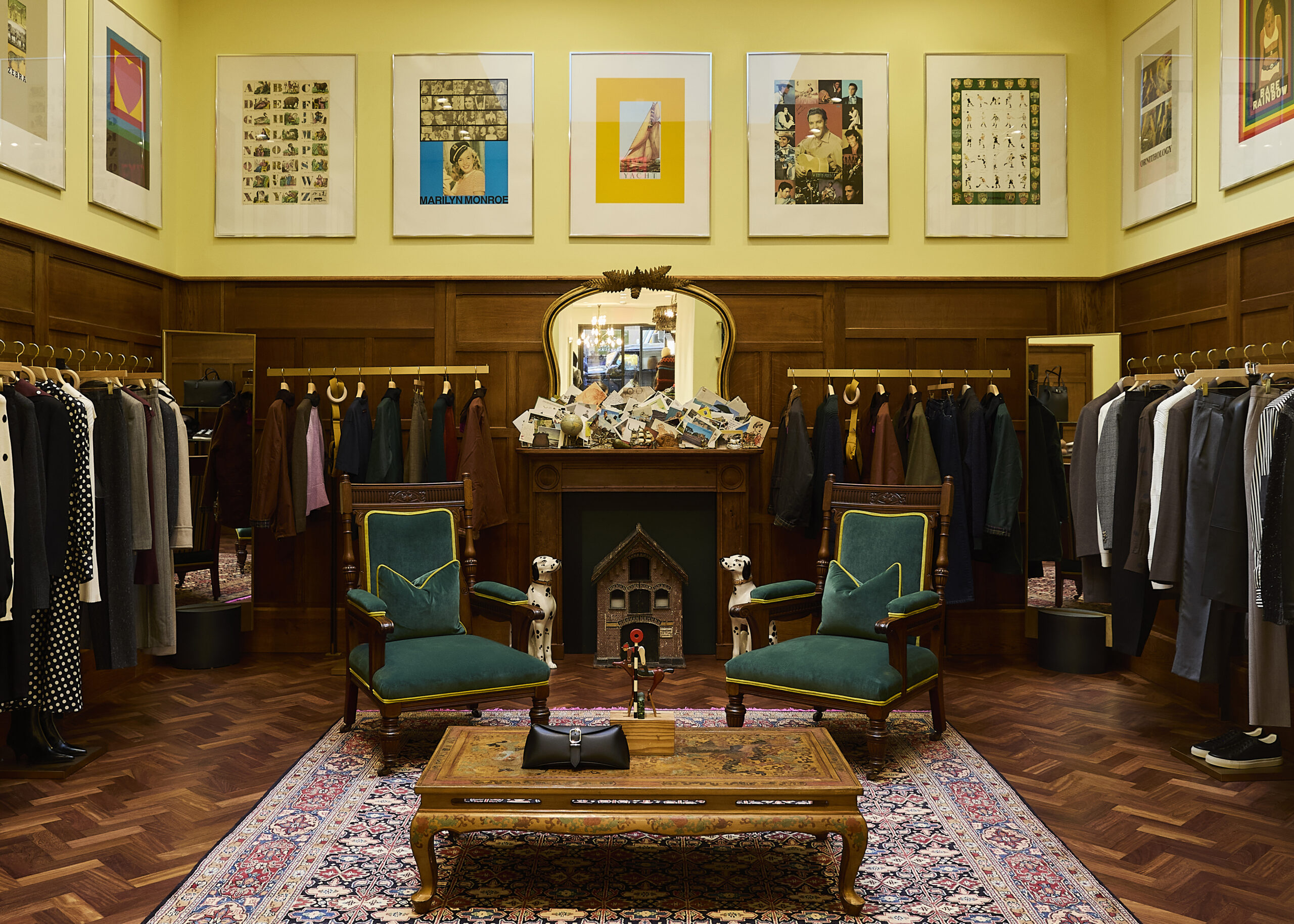 Wood-panelled room with green chairs, clothing rails and framed artwork at Paul Smith Madison Avenue