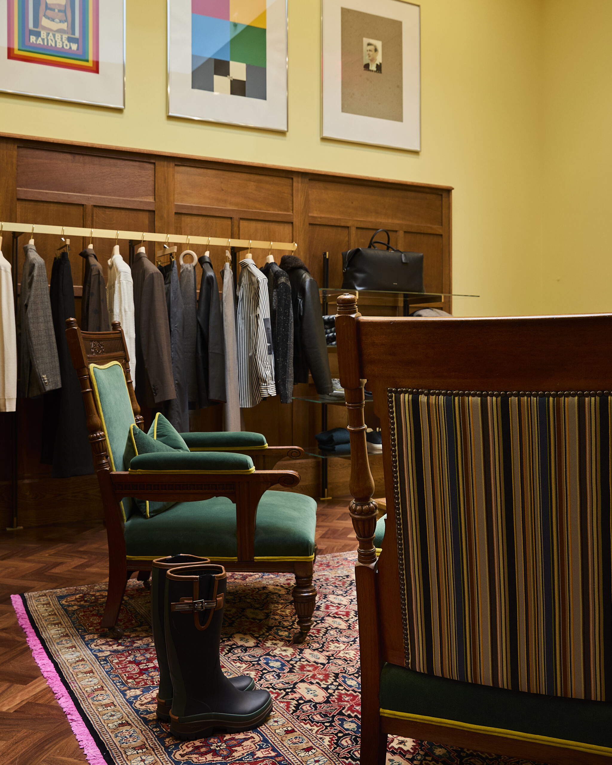 Green upholstered wooden chairs beside clothing rails at Paul Smith Madison Avenue